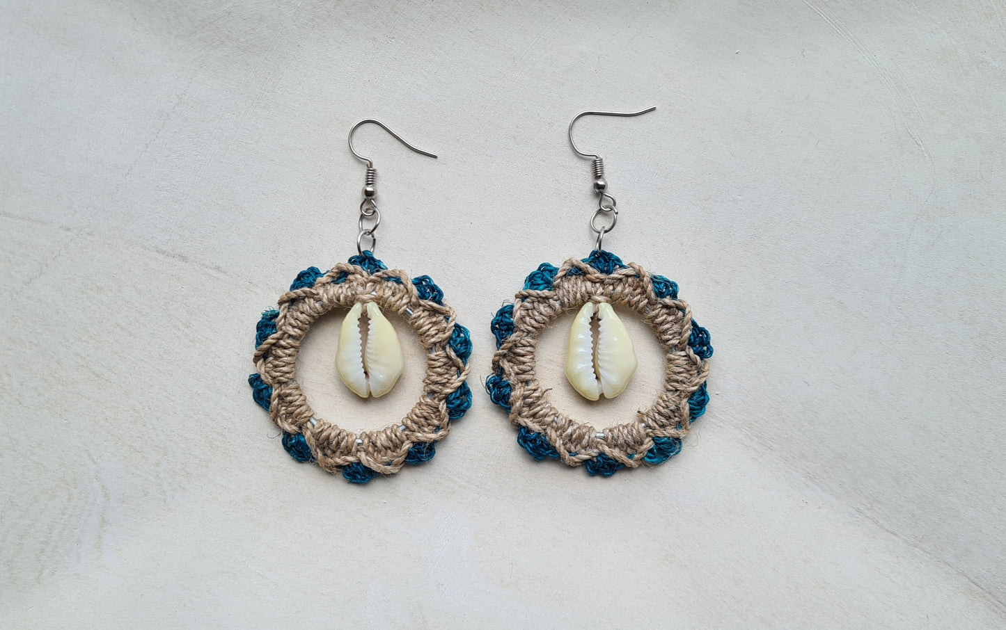 Pair of Turquoise patterned Sepik Cowrie earrings with shell accents on a light background, Front view