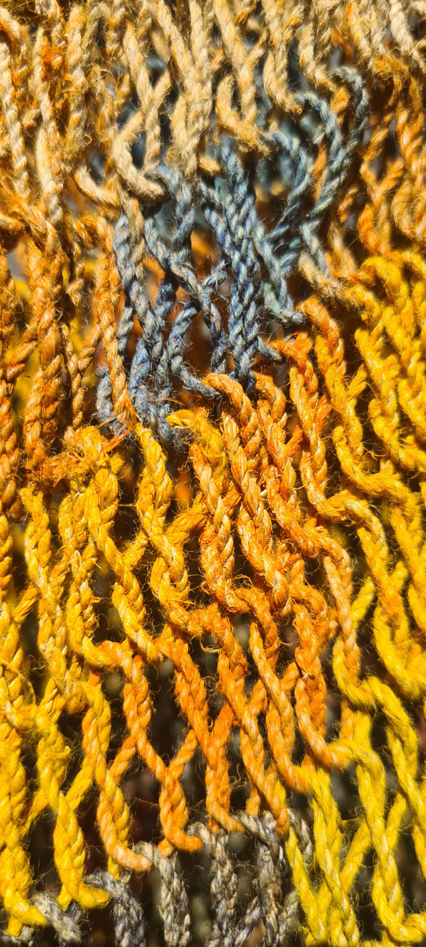 Handmade Natural Fibre Tulip Bilum Bag with Rainbow pattern on light background, Close Up view