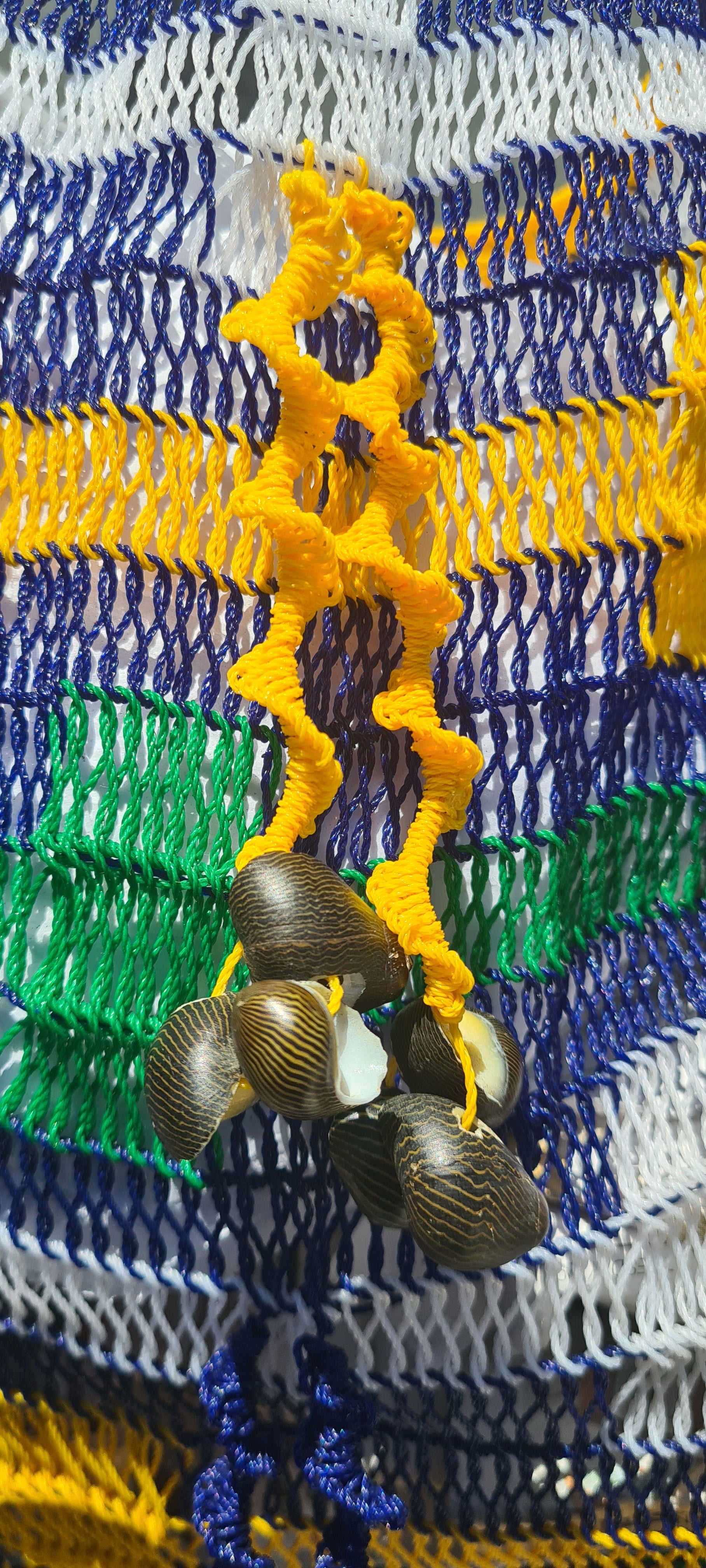 Handmade Morobe Nylon String Bilum Bag with Blue pattern on light background, Close up view of Yellow tassel and shells