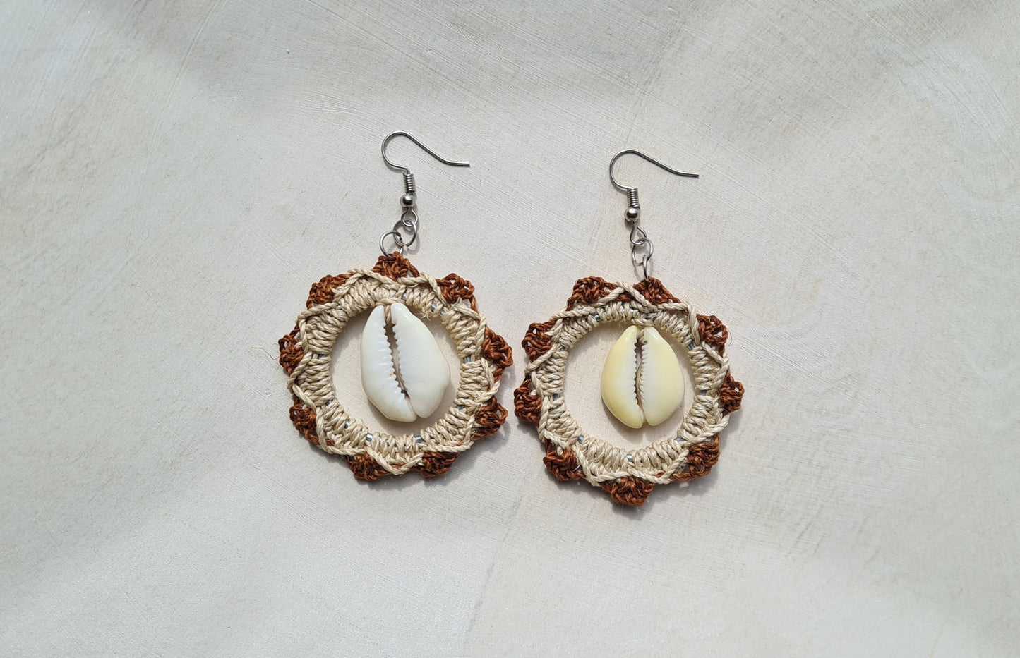 Pair of Brown patterned Sepik Cowrie earrings with shell accents on a light background, Front view