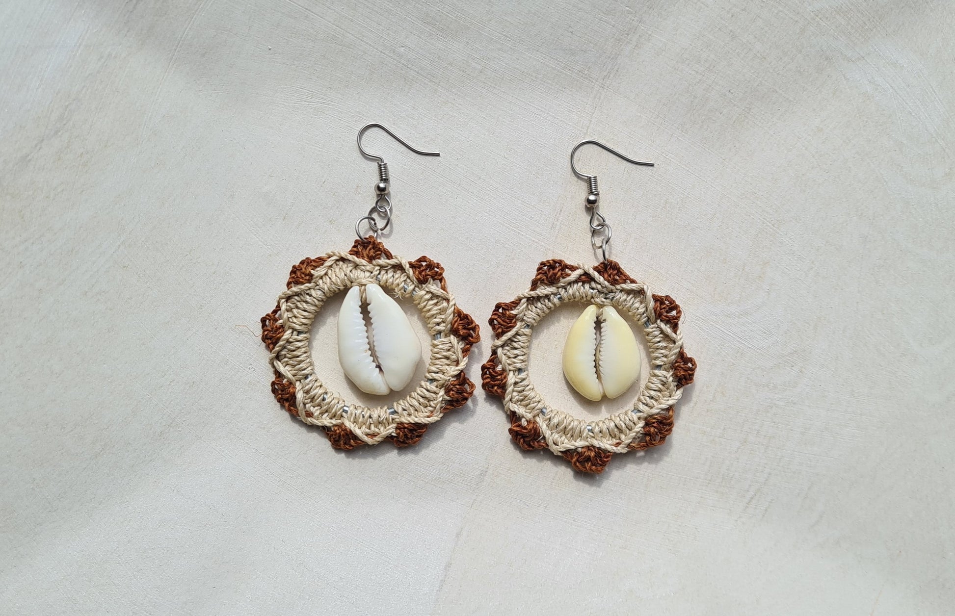Pair of Brown patterned Sepik Cowrie earrings with shell accents on a light background, Front view