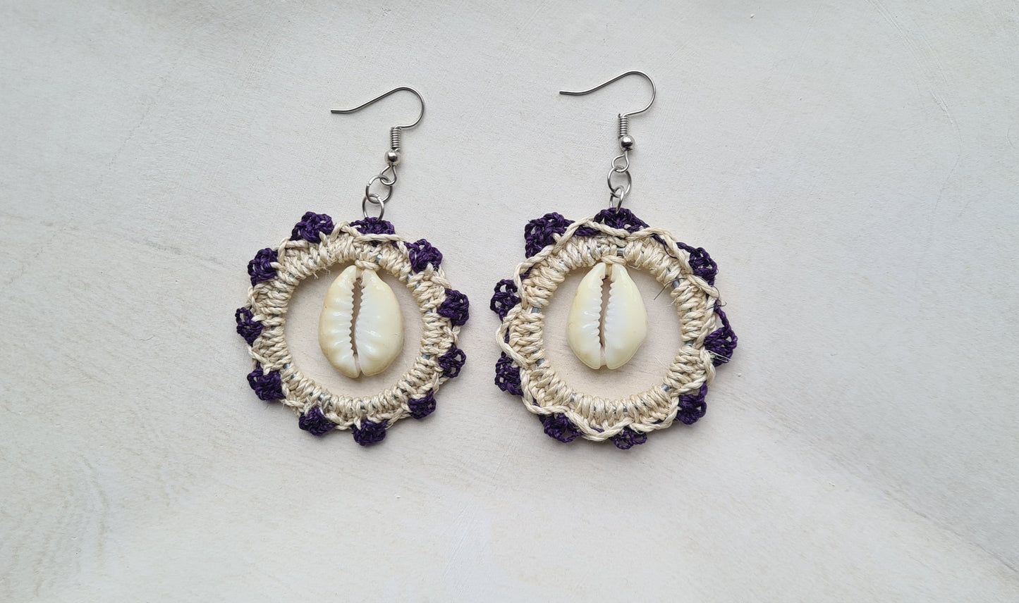 Pair of Indigo patterned Sepik Cowrie earrings with shell accents on a light background, Front view