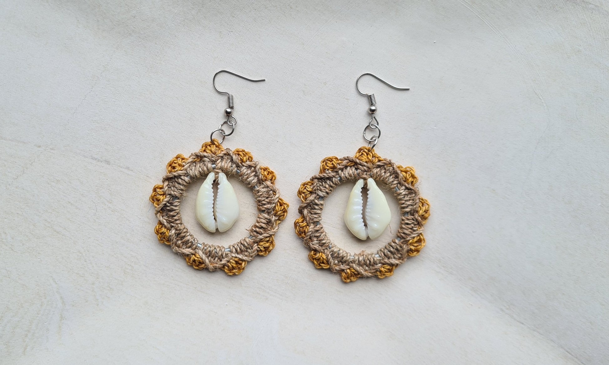 Pair of Pastel Orange patterned Sepik Cowrie earrings with shell accents on a light background, Front view