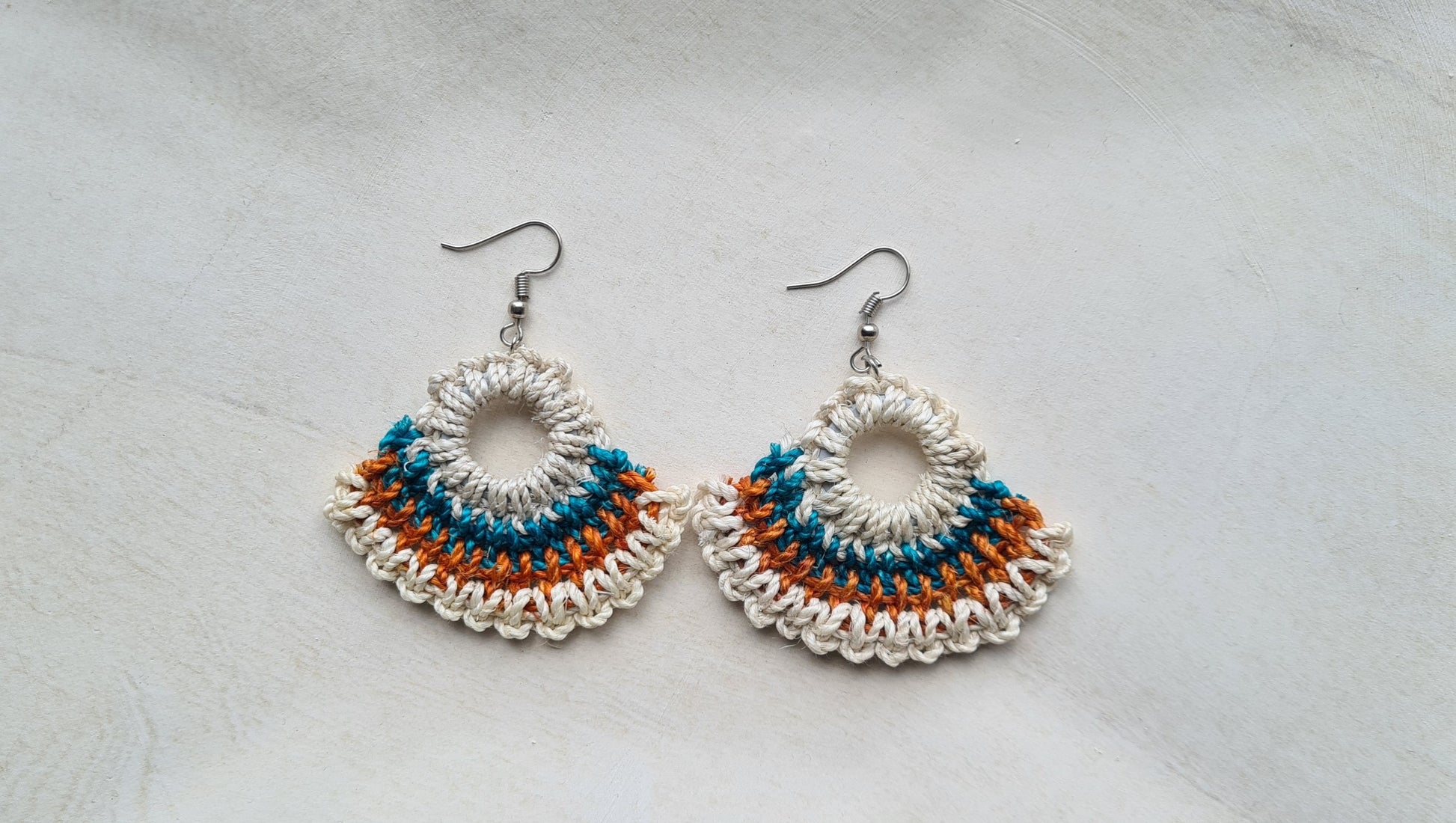 Pair of Kanu patterned Sepik Handwoven earrings on a light background, Front view